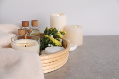 Photo of Spa composition with burning candles on light grey table, closeup. Space for text