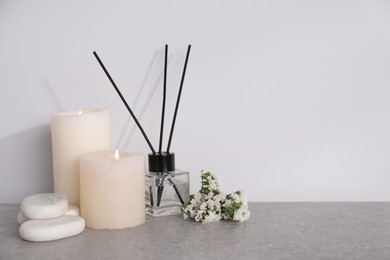 Photo of Spa composition with burning candles and reed diffuser on light grey table, space for text