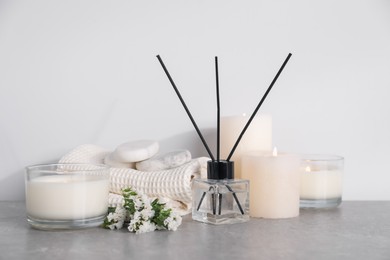 Photo of Spa composition with burning candles and reed diffuser on light grey table