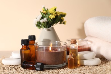 Photo of Spa composition with burning candles on table against beige background, closeup