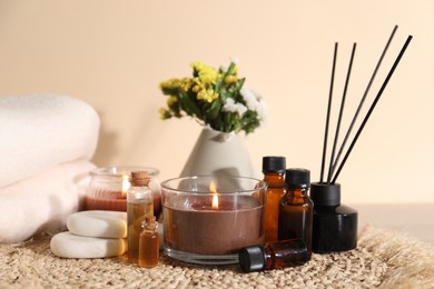 Photo of Spa composition with burning candles on wooden table against beige background, closeup