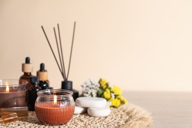 Photo of Spa composition with burning candles on wooden table against beige background, space for text