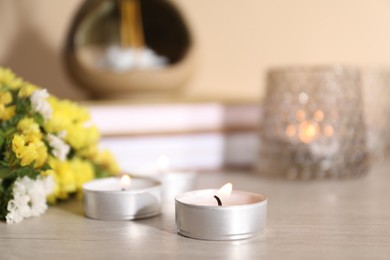 Photo of Spa composition with burning candles on wooden table against beige background, closeup