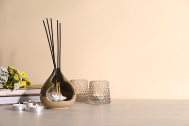 Photo of Spa composition with burning candles on wooden table against beige background, space for text