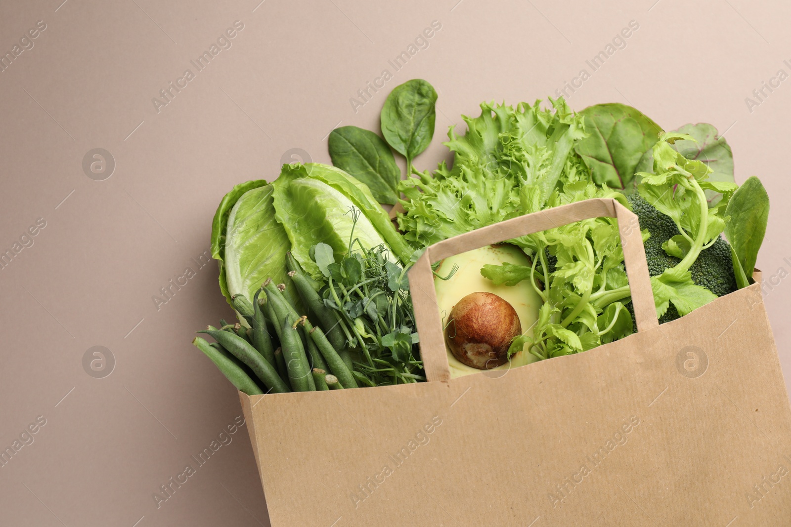 Photo of Superfood. Different healthy products in paper bag on beige background, top view