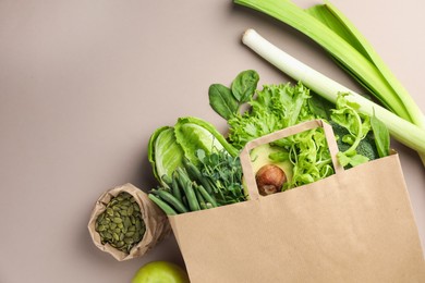 Photo of Superfood. Different healthy products in paper bag on beige background, top view. Space for text