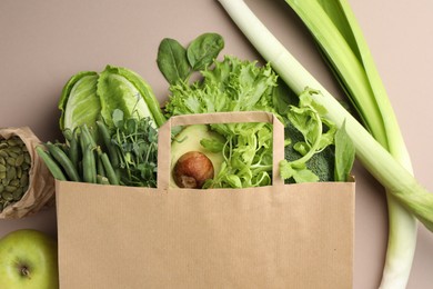 Photo of Superfood. Different healthy products in paper bag on beige background, top view