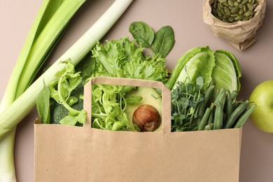 Photo of Superfood. Different healthy products in paper bag on beige background, top view