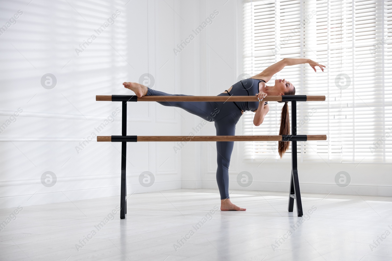 Professional dancer stretching at barre in studio Photo of Professional dancer stretching at barre in studio