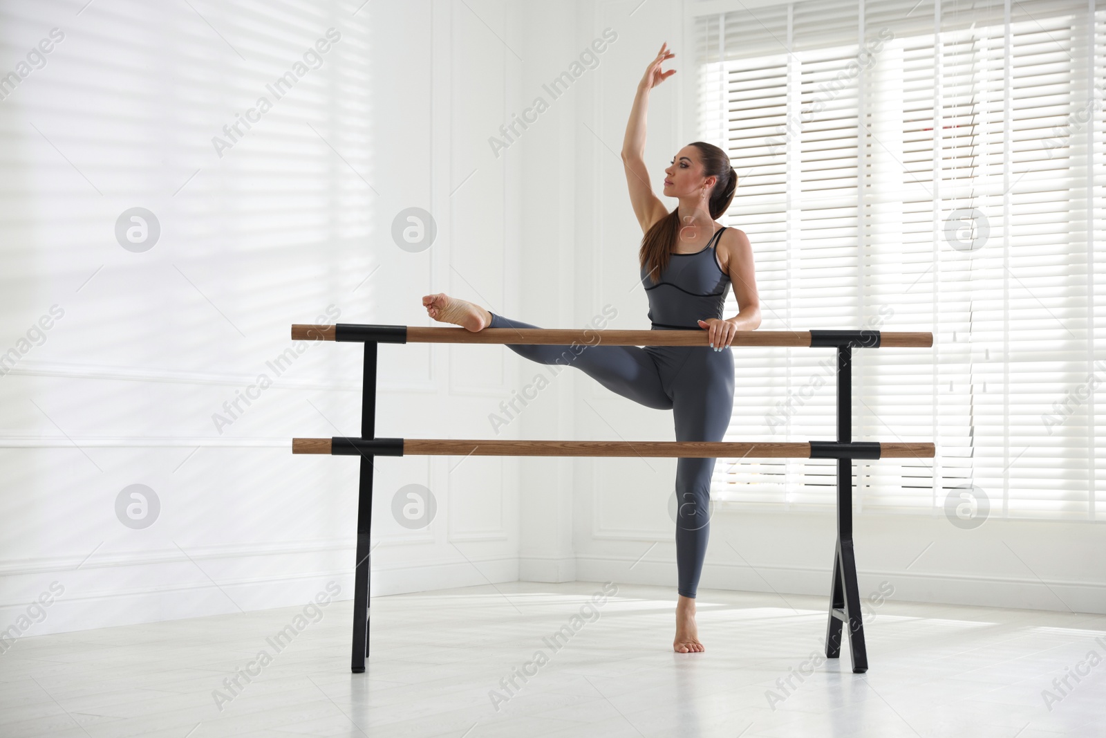 Professional dancer stretching at barre in studio Photo of Professional dancer stretching at barre in studio