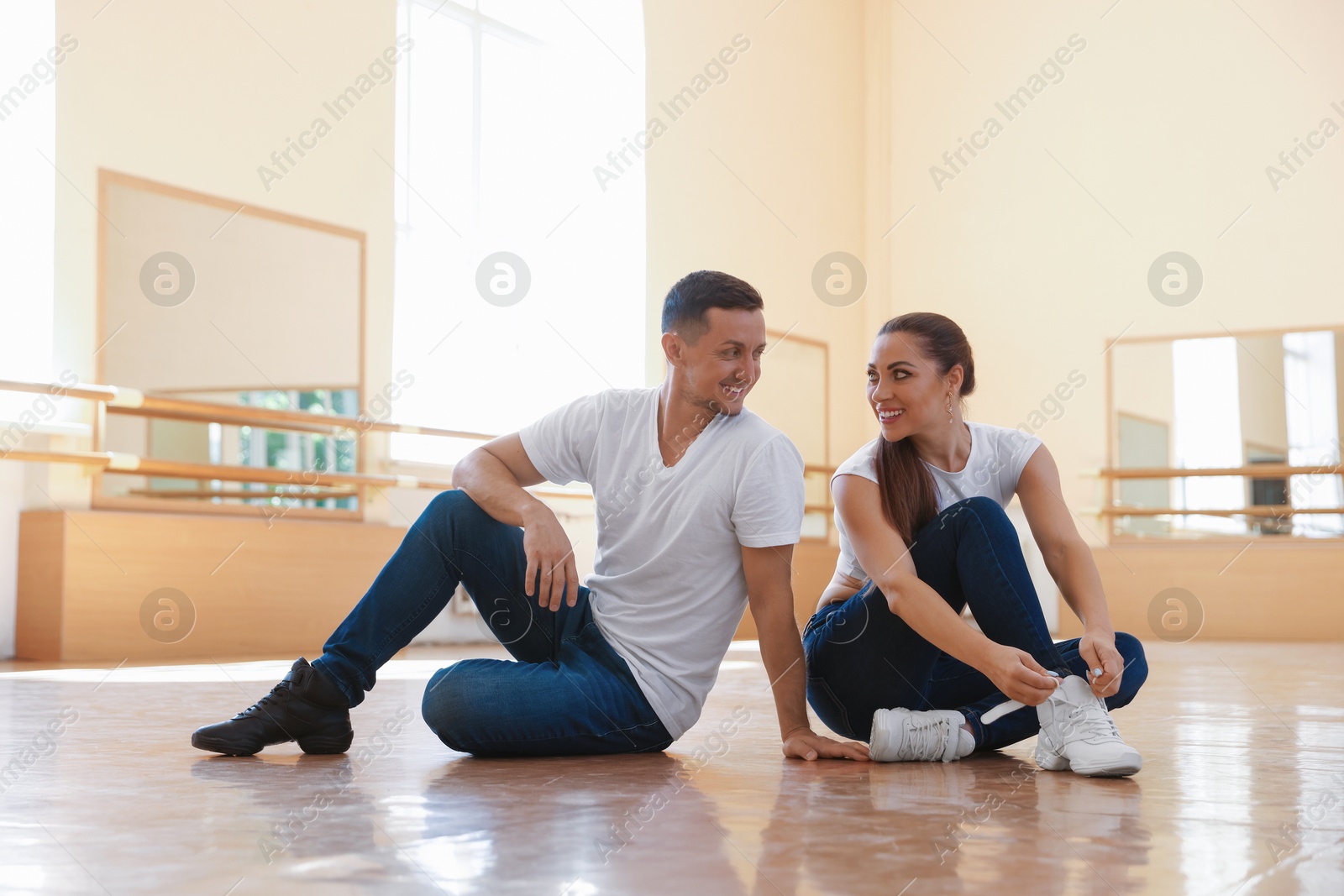 Man and woman tying her shoelaces in dance studio Photo of Man and woman tying her shoelaces in dance studio