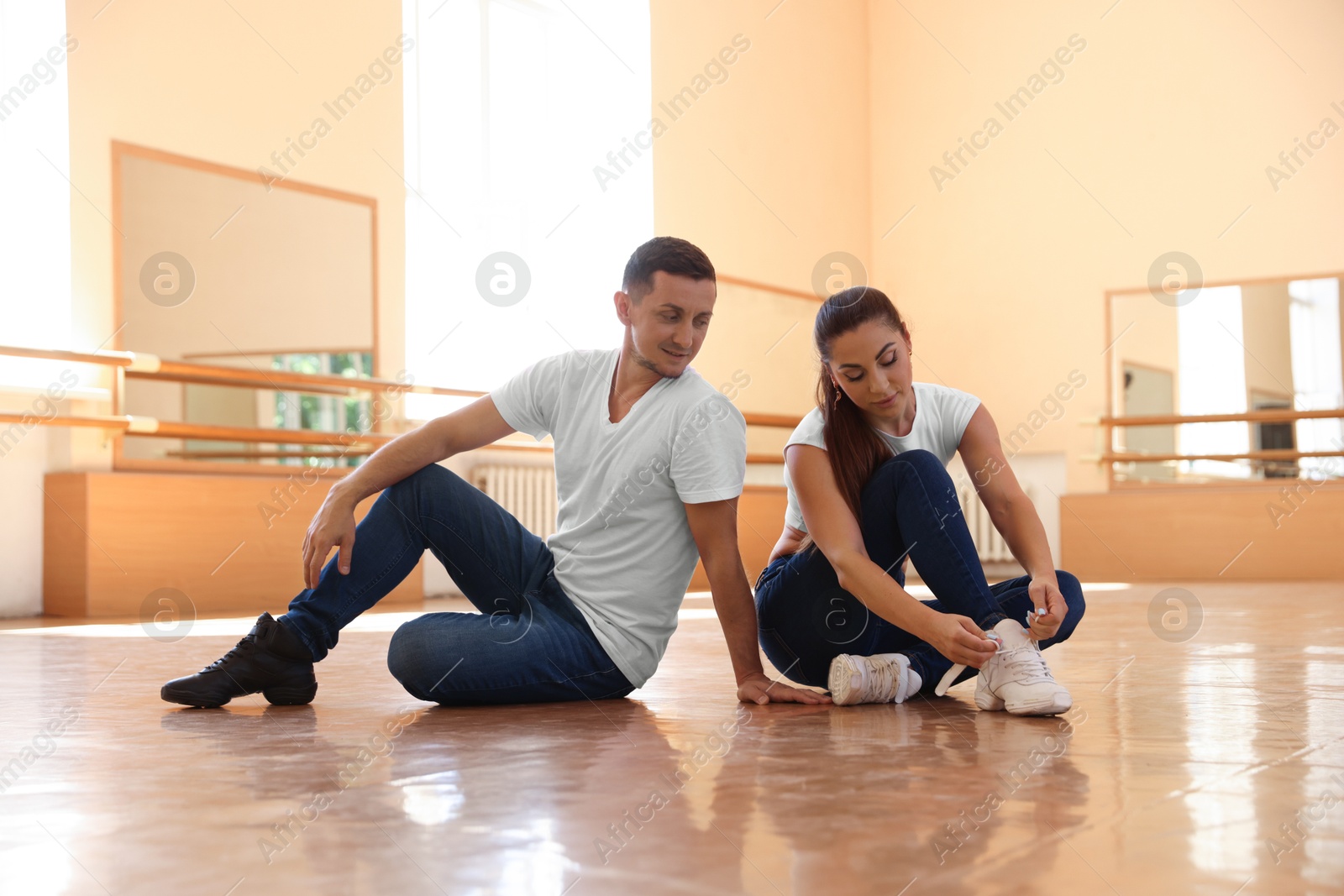 Man and woman tying her shoelaces in dance studio Photo of Man and woman tying her shoelaces in dance studio