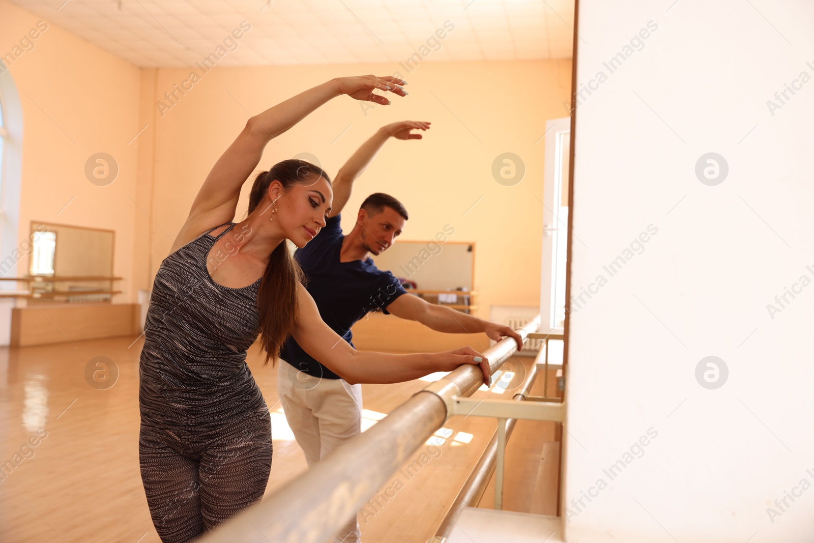 Couple of professional dancers stretching at barre in studio, selective focus Photo of Couple of professional dancers stretching at barre in studio, selective focus
