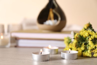 Photo of Spa composition with burning candles on wooden table against beige background, closeup