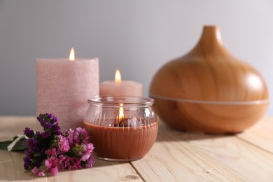 Photo of Spa composition with flowers and burning candles on wooden table against grey background, closeup