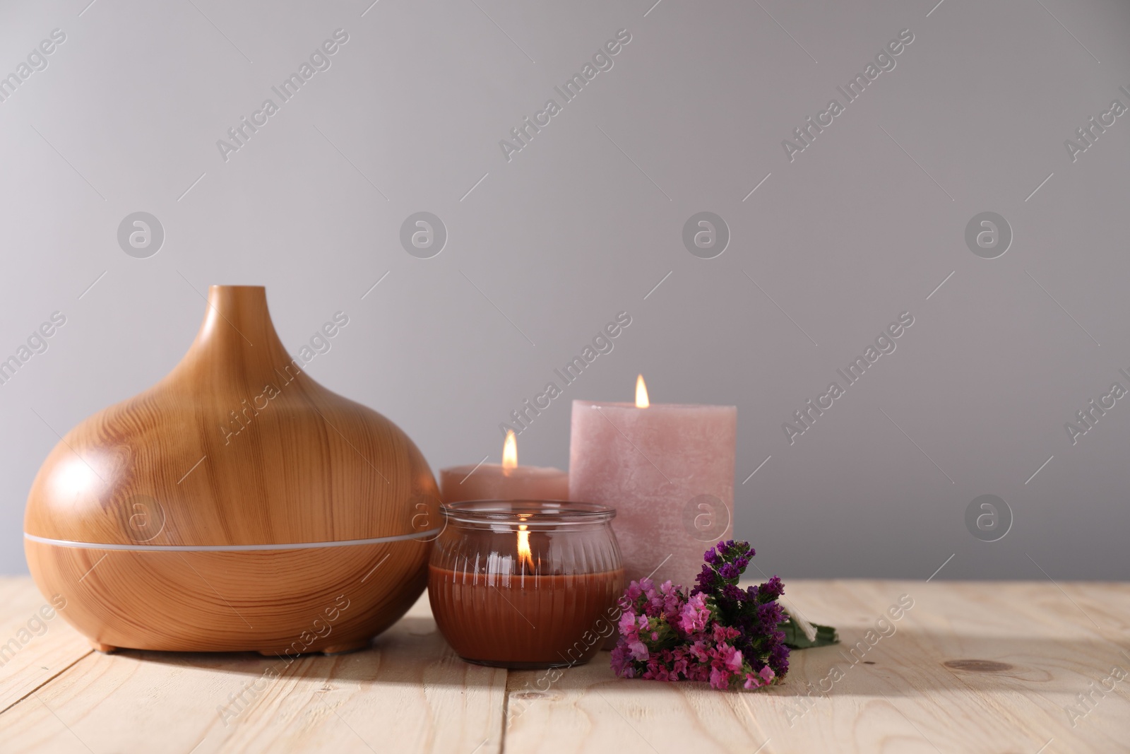 Spa composition with flowers and burning candles on wooden table against grey background, closeup Photo of Spa composition with flowers and burning candles on wooden table against grey background, closeup