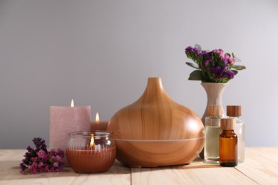 Photo of Spa composition with flowers and burning candles on wooden table against grey background, closeup