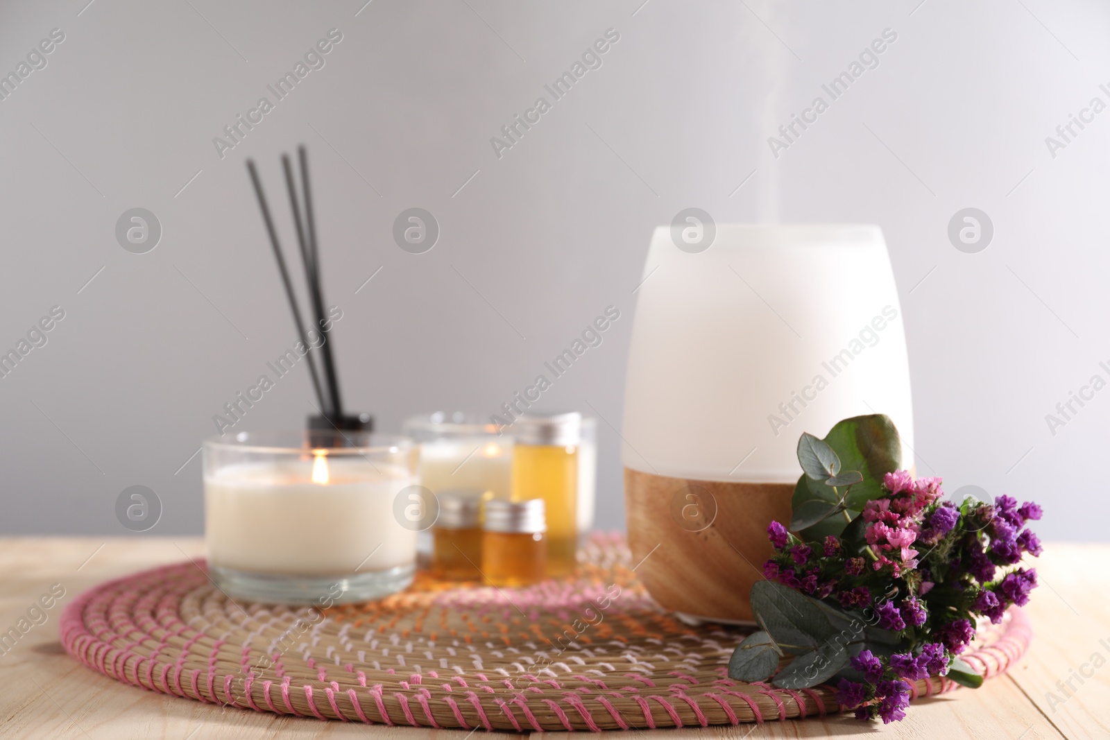 Spa composition with burning candles and aroma oil diffuser on wooden table against light grey background, closeup Photo of Spa composition with burning candles and aroma oil diffuser on wooden table against light grey background, closeup