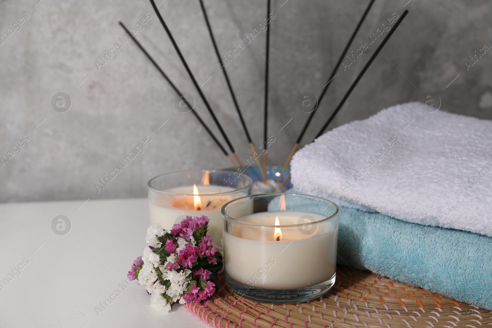 Spa composition with burning candles on white wooden table near grey wall, closeup. Space for text Photo of Spa composition with burning candles on white wooden table near grey wall, closeup. Space for text