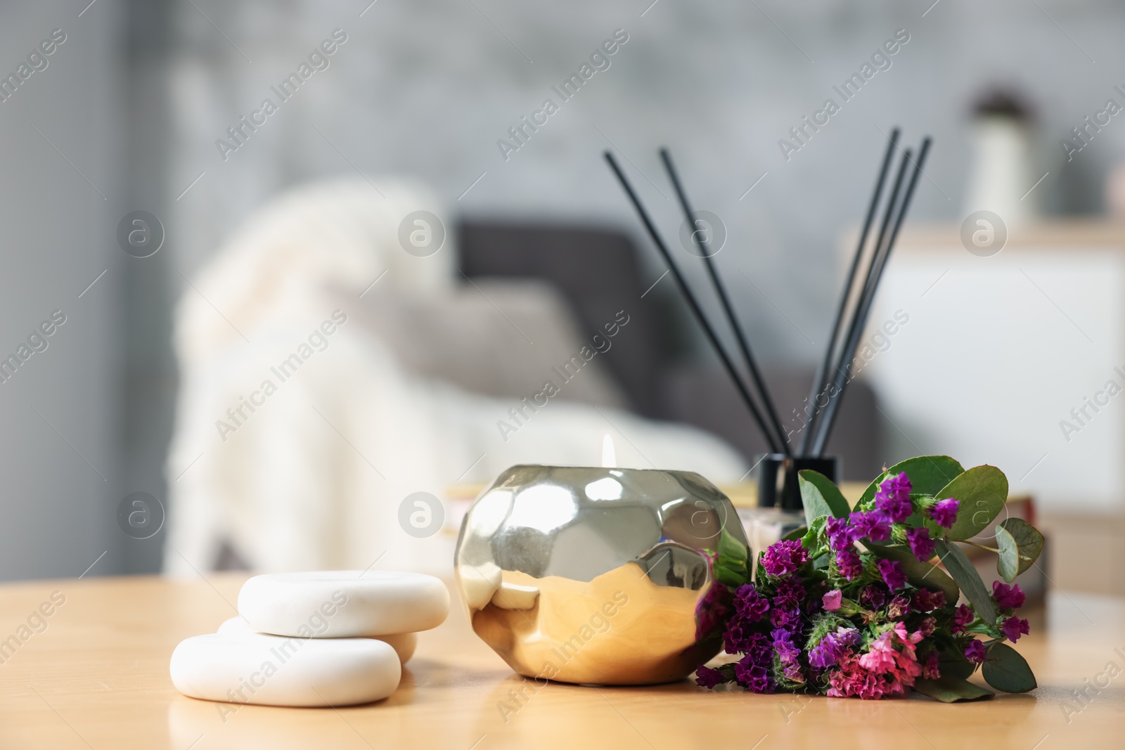 Spa composition with burning candle and reed diffuser on wooden table indoors, closeup Photo of Spa composition with burning candle and reed diffuser on wooden table indoors, closeup