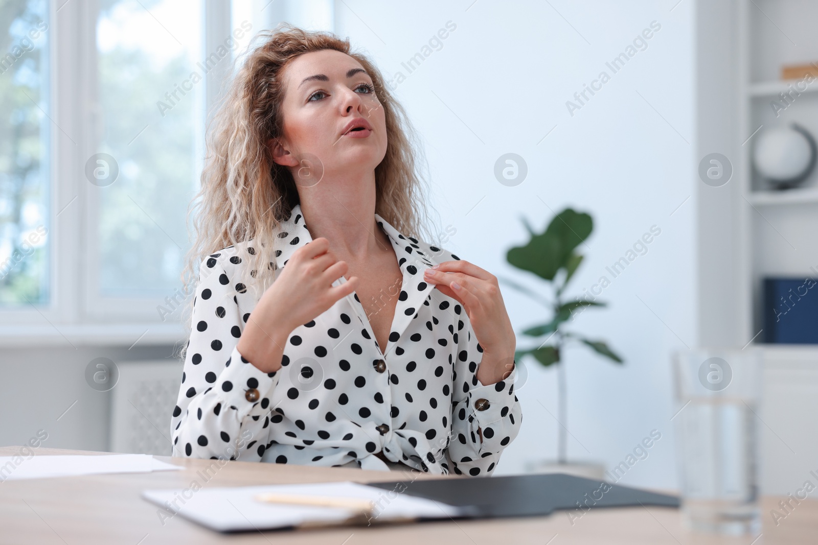 Air conditioning. Woman suffering from heat at workplace in office Photo of Air conditioning. Woman suffering from heat at workplace in office