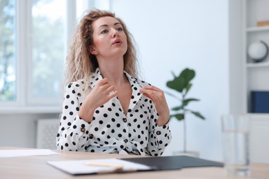 Photo of Air conditioning. Woman suffering from heat at workplace in office