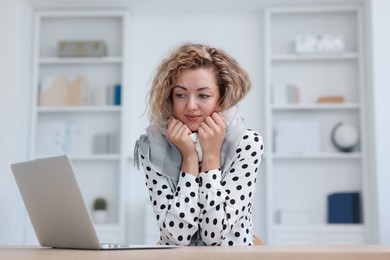 Photo of Air conditioning. Woman with scarf suffering from cold temperature at workplace in office