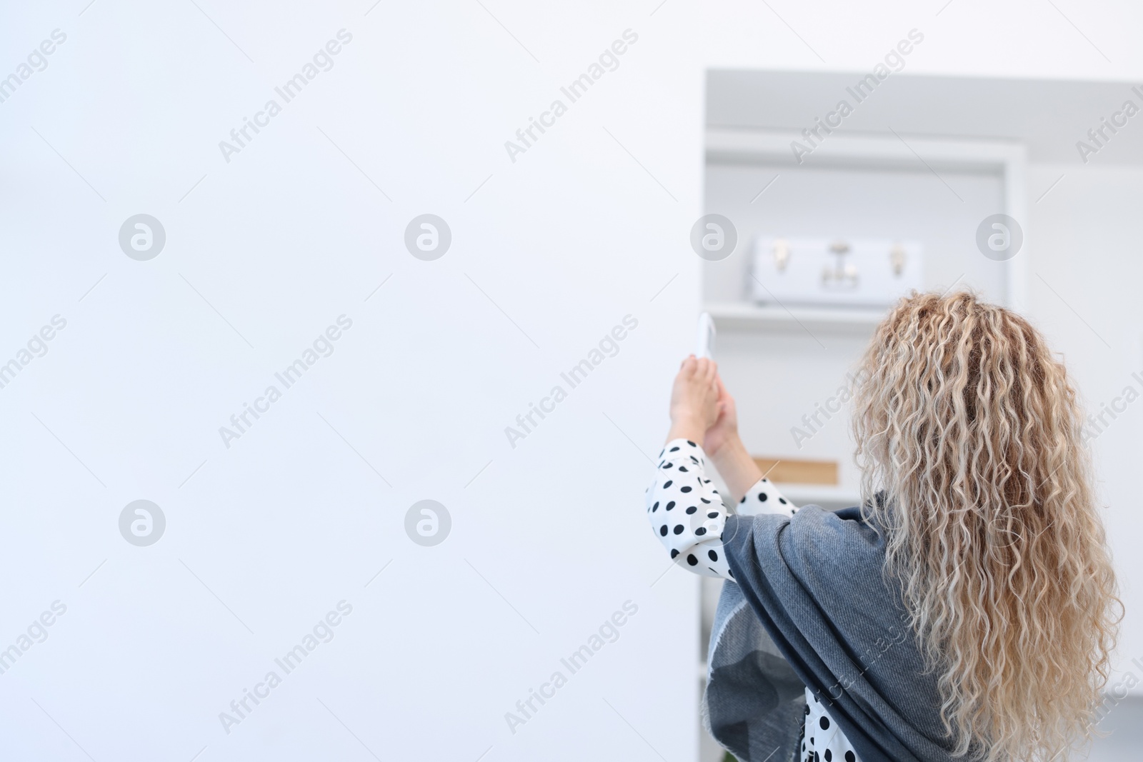 Woman using remote to control air conditioner in office, back view Photo of Woman using remote to control air conditioner in office, back view