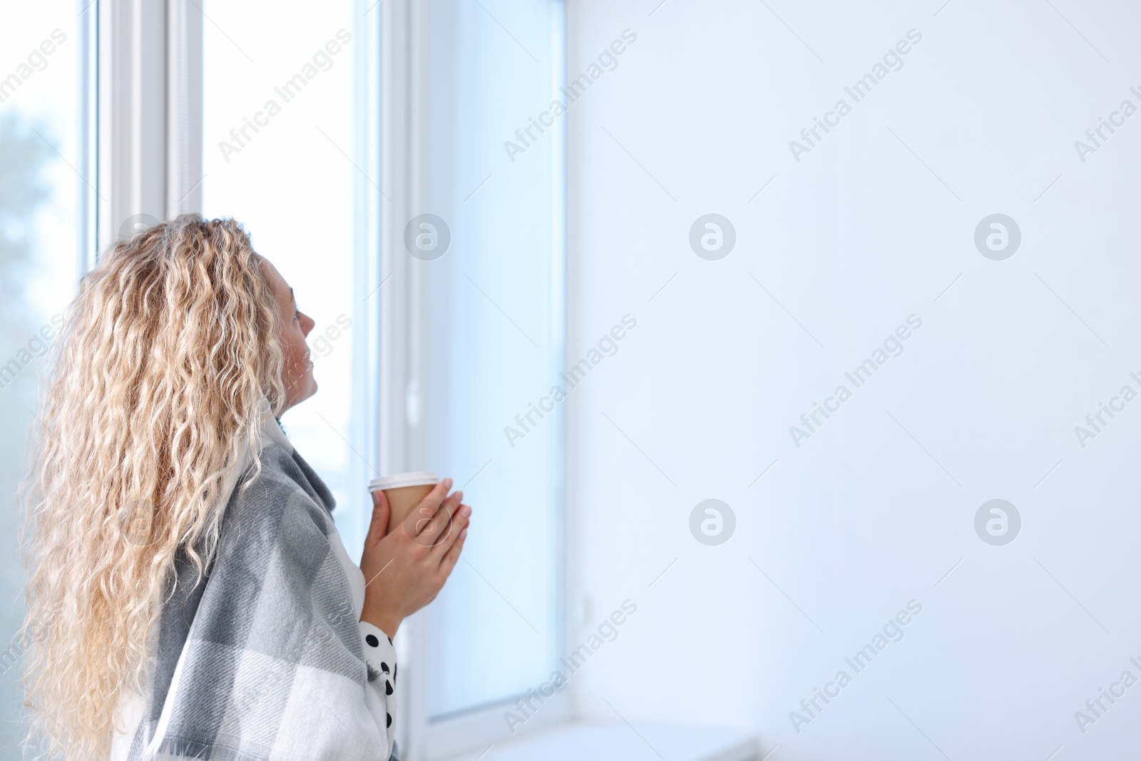 Woman with scarf and cup of hot drink near air conditioner in office Photo of Woman with scarf and cup of hot drink near air conditioner in office