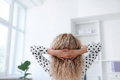 Photo of Woman sitting at workplace in office with air conditioning, back view