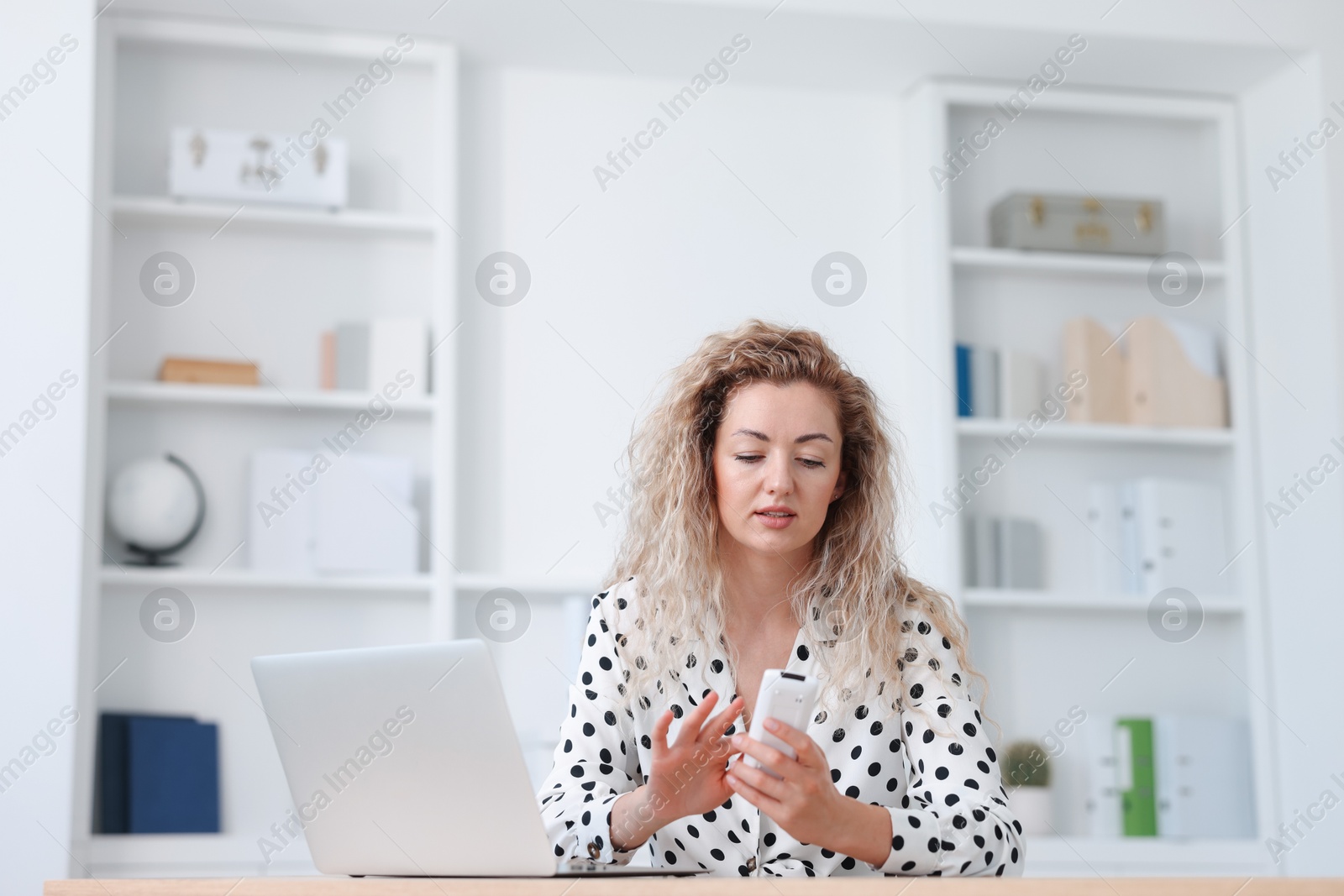 Woman using remote to control air conditioner in office Photo of Woman using remote to control air conditioner in office