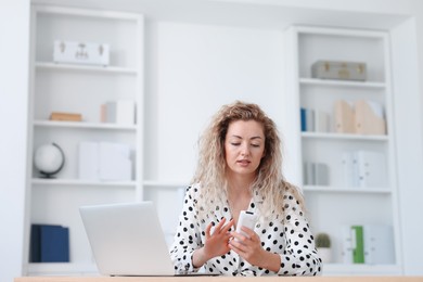 Photo of Woman using remote to control air conditioner in office