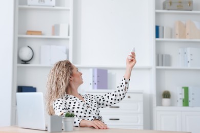 Photo of Woman using remote to control air conditioner in office