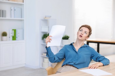 Photo of Air conditioning. Woman suffering from heat at workplace in office
