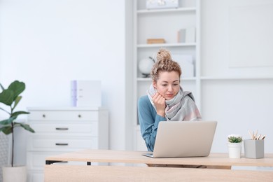 Photo of Air conditioning. Woman with scarf suffering from cold temperature at workplace in office