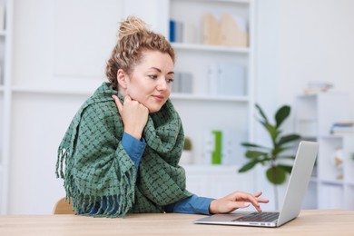 Photo of Air conditioning. Woman with scarf suffering from cold temperature at workplace in office