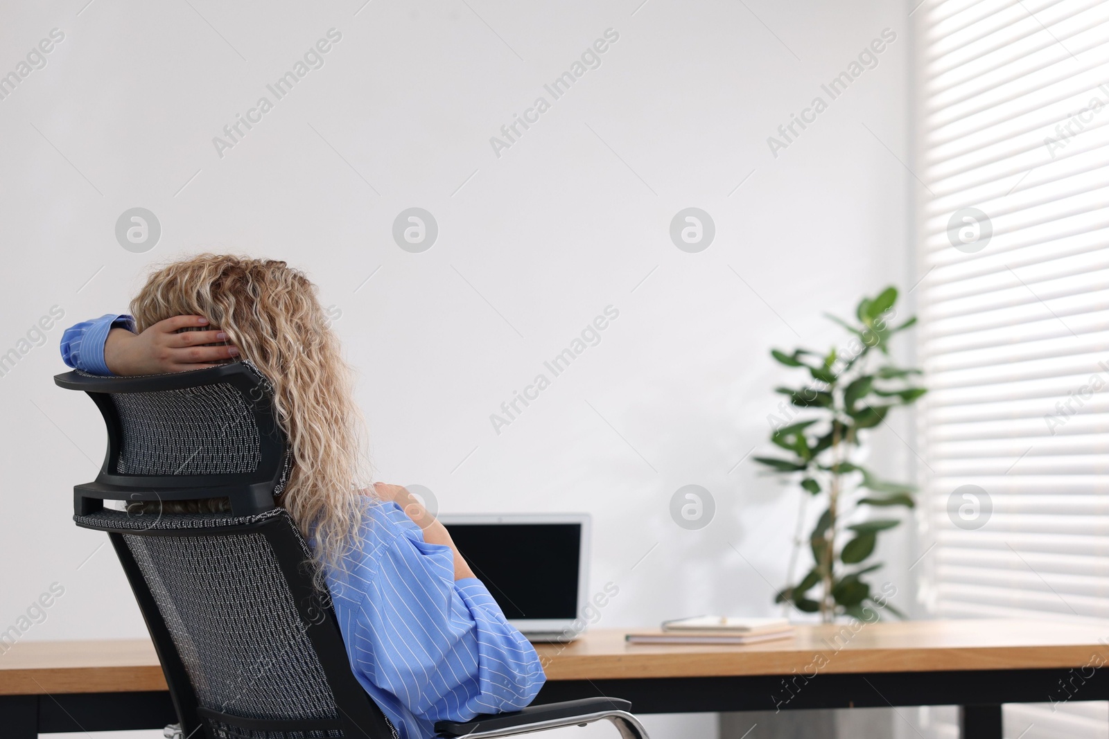 Photo of Woman sitting at workplace in office with air conditioning, back view