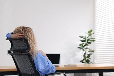 Photo of Woman sitting at workplace in office with air conditioning, back view
