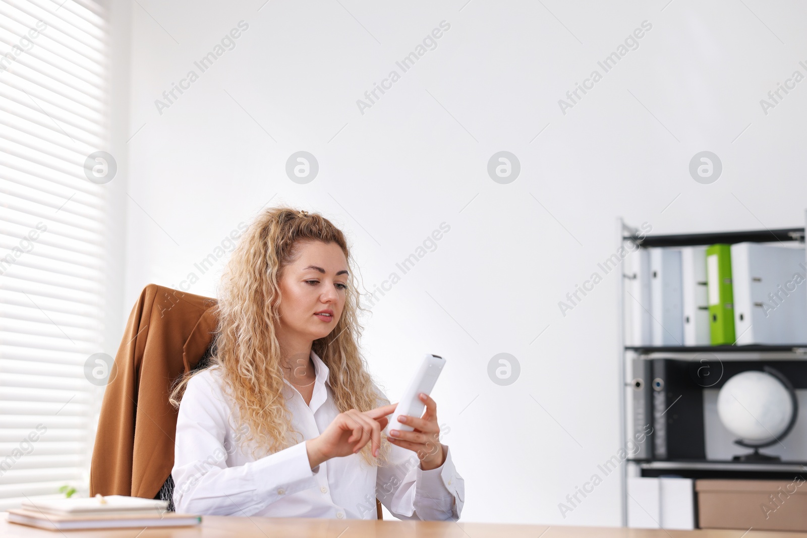 Woman using remote to control air conditioner in office Photo of Woman using remote to control air conditioner in office