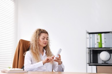 Photo of Woman using remote to control air conditioner in office