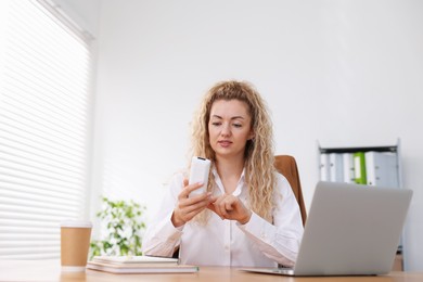 Photo of Woman using remote to control air conditioner in office