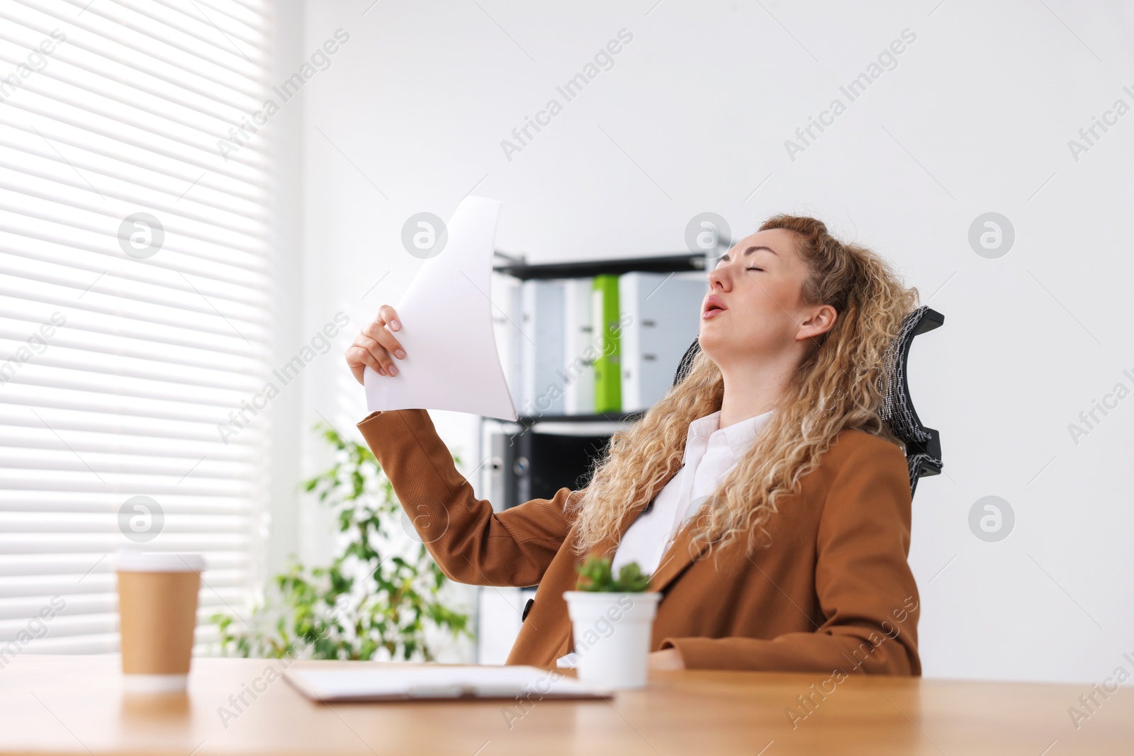 Air conditioning. Woman suffering from heat at workplace in office Photo of Air conditioning. Woman suffering from heat at workplace in office