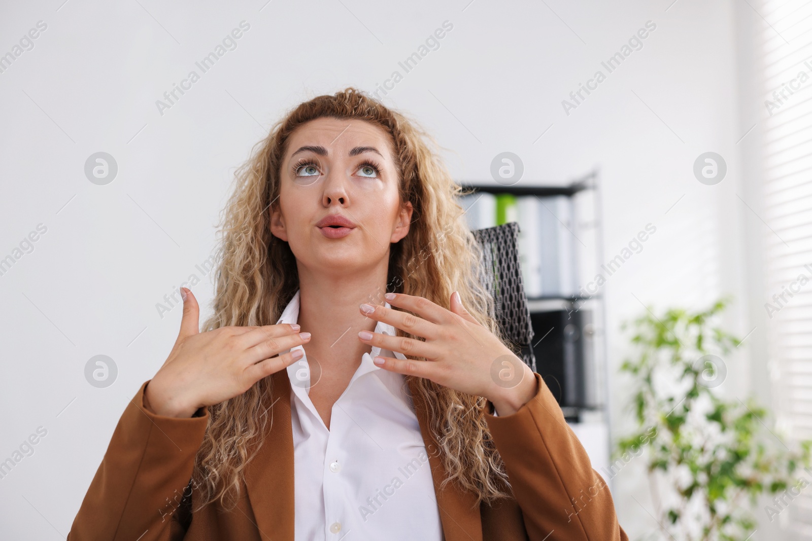 Air conditioning. Woman suffering from heat at workplace in office Photo of Air conditioning. Woman suffering from heat at workplace in office