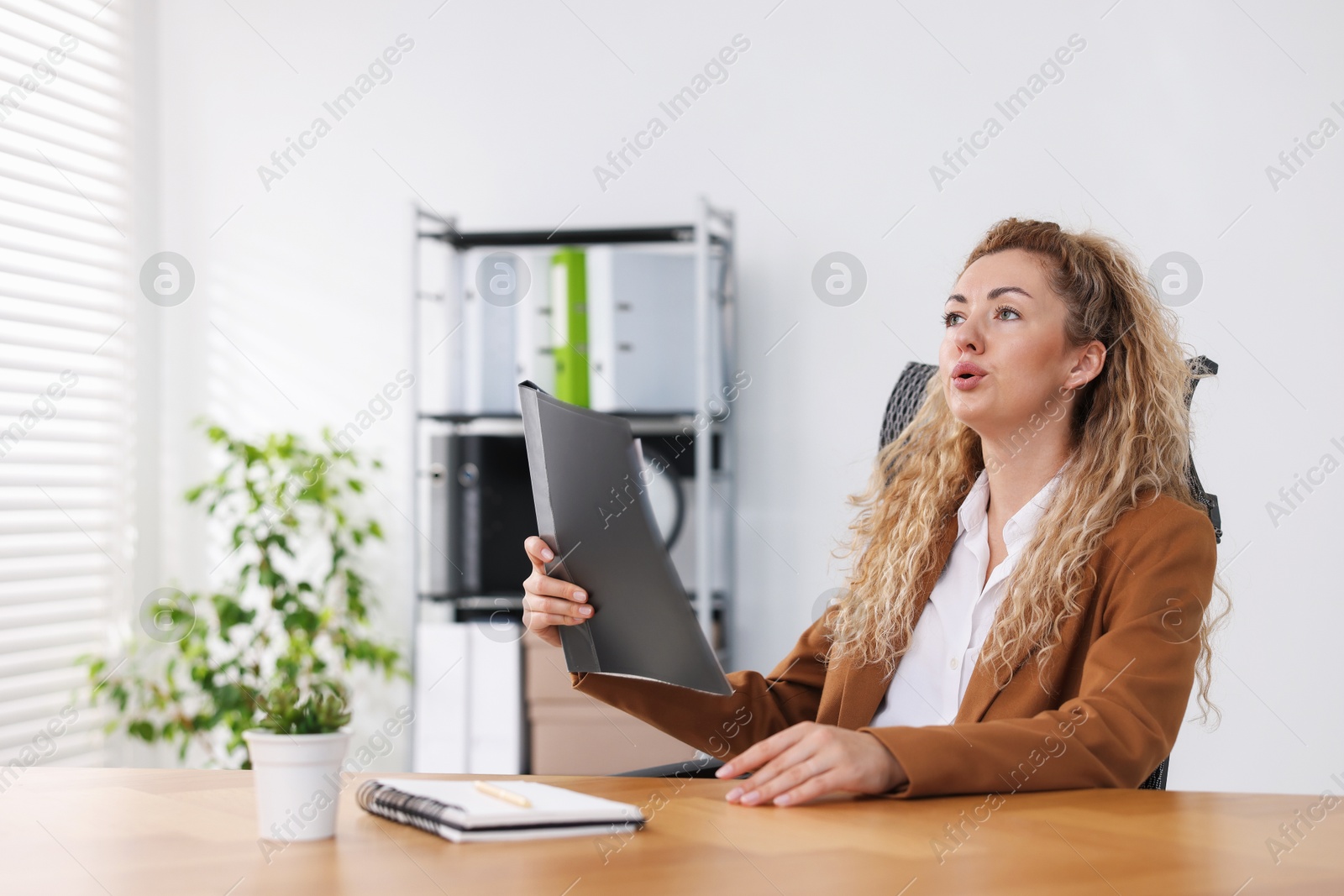 Air conditioning. Woman suffering from heat at workplace in office Photo of Air conditioning. Woman suffering from heat at workplace in office