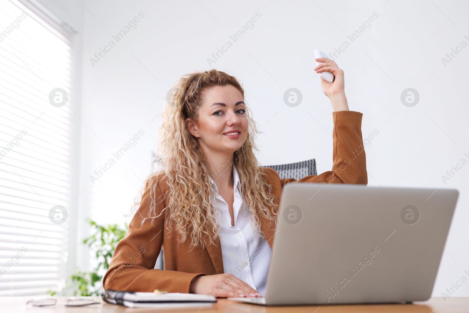 Woman using remote to control air conditioner in office Photo of Woman using remote to control air conditioner in office