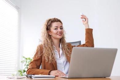 Photo of Woman using remote to control air conditioner in office