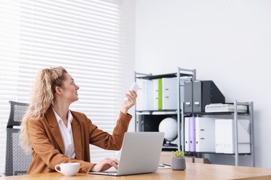Photo of Woman using remote to control air conditioner in office