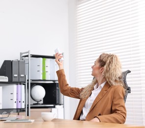 Photo of Woman using remote to control air conditioner in office