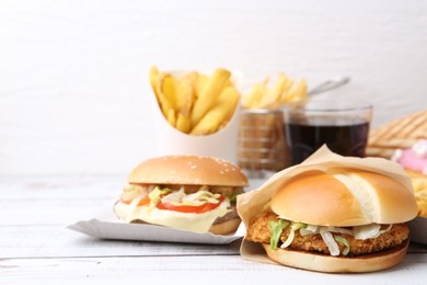 Photo of Different delicious fast food on light wooden table against white background, closeup