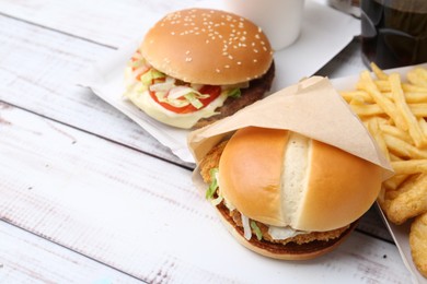 Photo of Different delicious fast food on light wooden table, closeup. Space for text